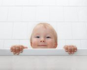 Ein Kind schaut über den Rand einer Badewanne