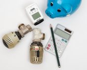 Thermostat, Messgerät, Stift, Taschenrechner und ein Sparschwein.