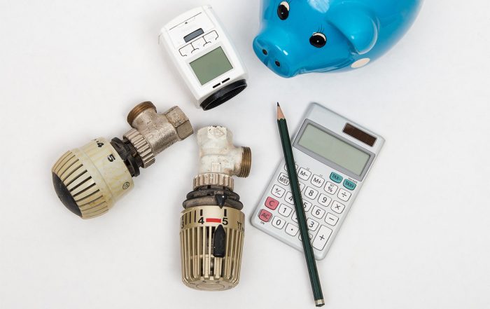 Thermostat, Messgerät, Stift, Taschenrechner und ein Sparschwein.