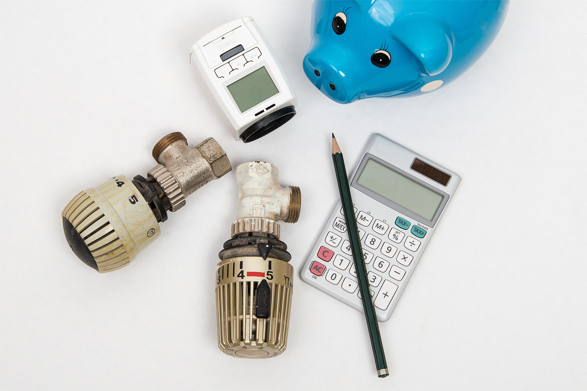 Thermostat, Messgerät, Stift, Taschenrechner und ein Sparschwein.