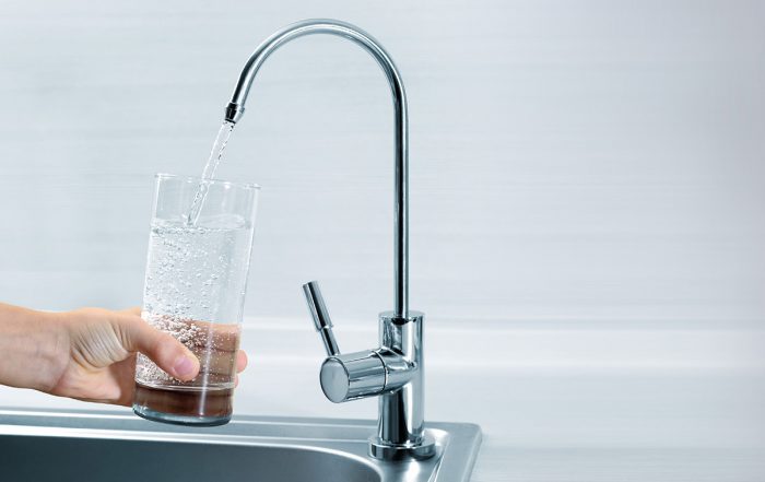 Ein Glas wird mit Trinkwasser von einem Wasserhahn befüllt.