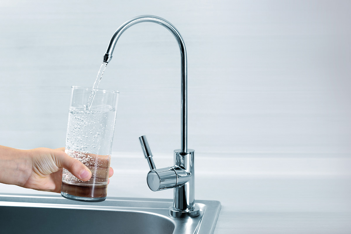 Ein Glas wird mit Trinkwasser von einem Wasserhahn befüllt.